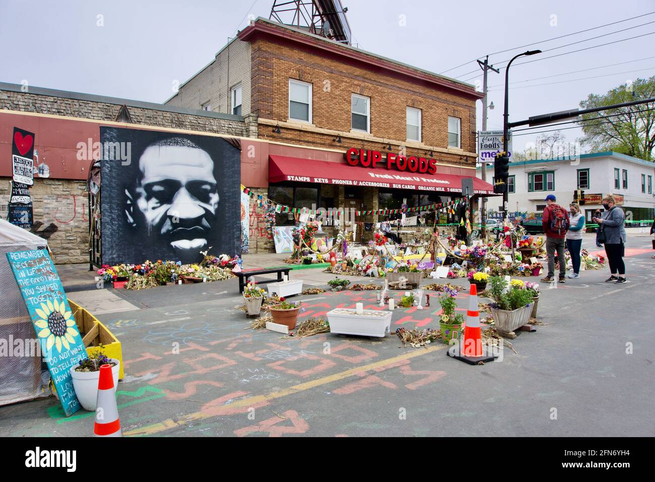 Visitors at George Floyd Memorial Square at 38th & Chicago. Cup Foods. Visitors pay respects at shrine and mural covered in flowers. Minneapolis, MN Stock Photo