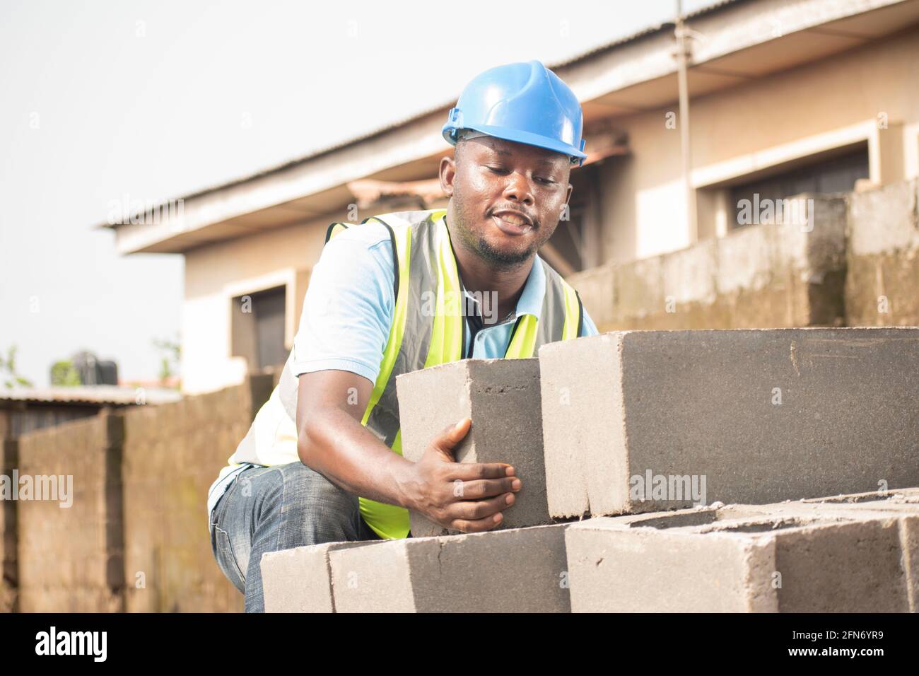 a building contractor lifting blocks on site,african bricklayer Stock