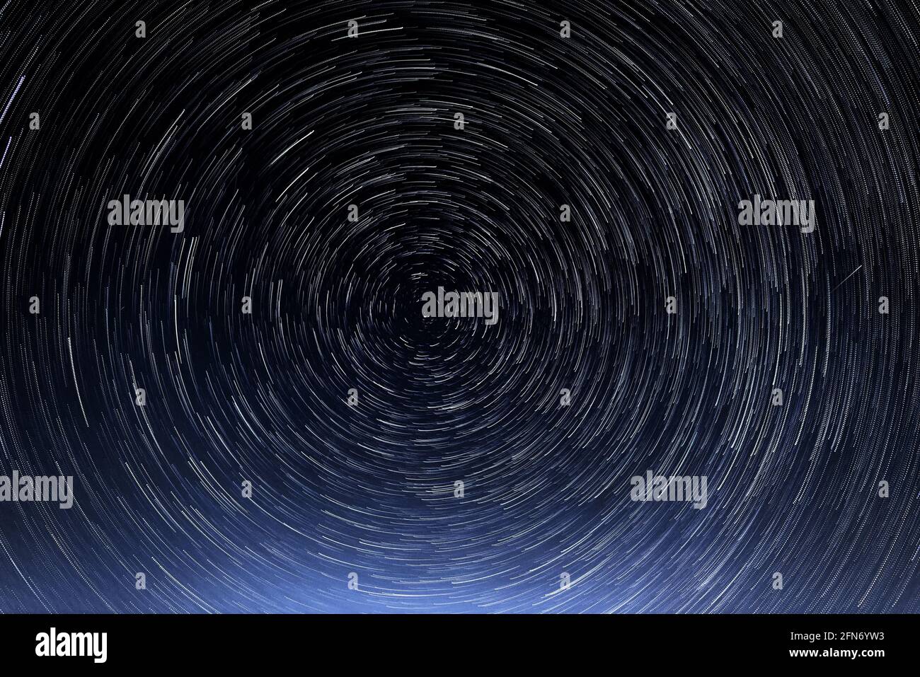 Stellar trails, the rotation of bright stars at night around the Polar Star  against a blue sky and a meteor Stock Photo - Alamy