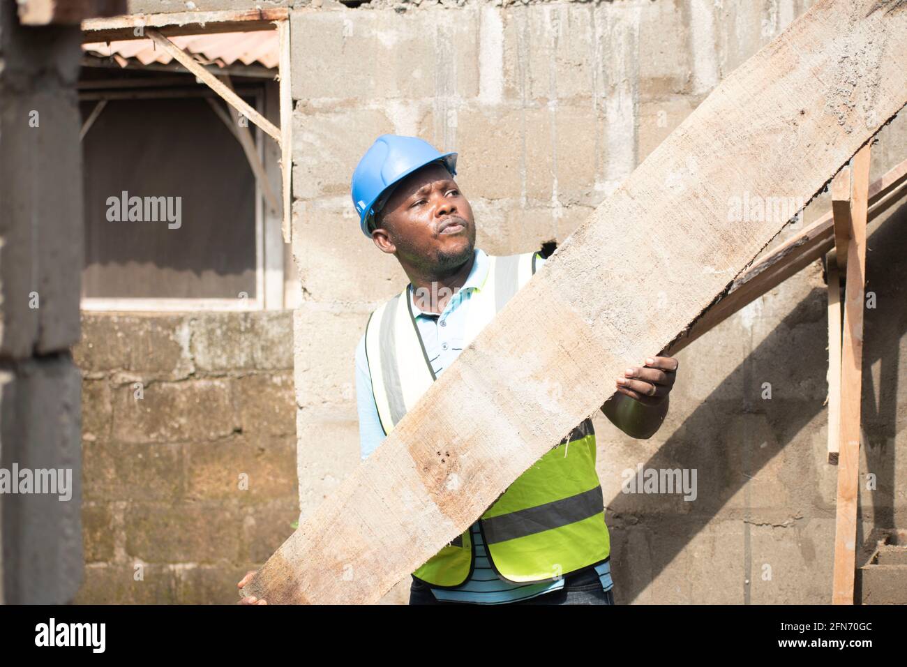 a carpenter carrying wood on site Stock Photo