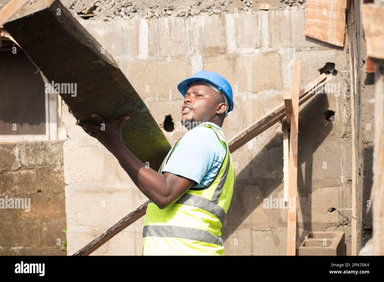 a carpenter carrying wood on site Stock Photo