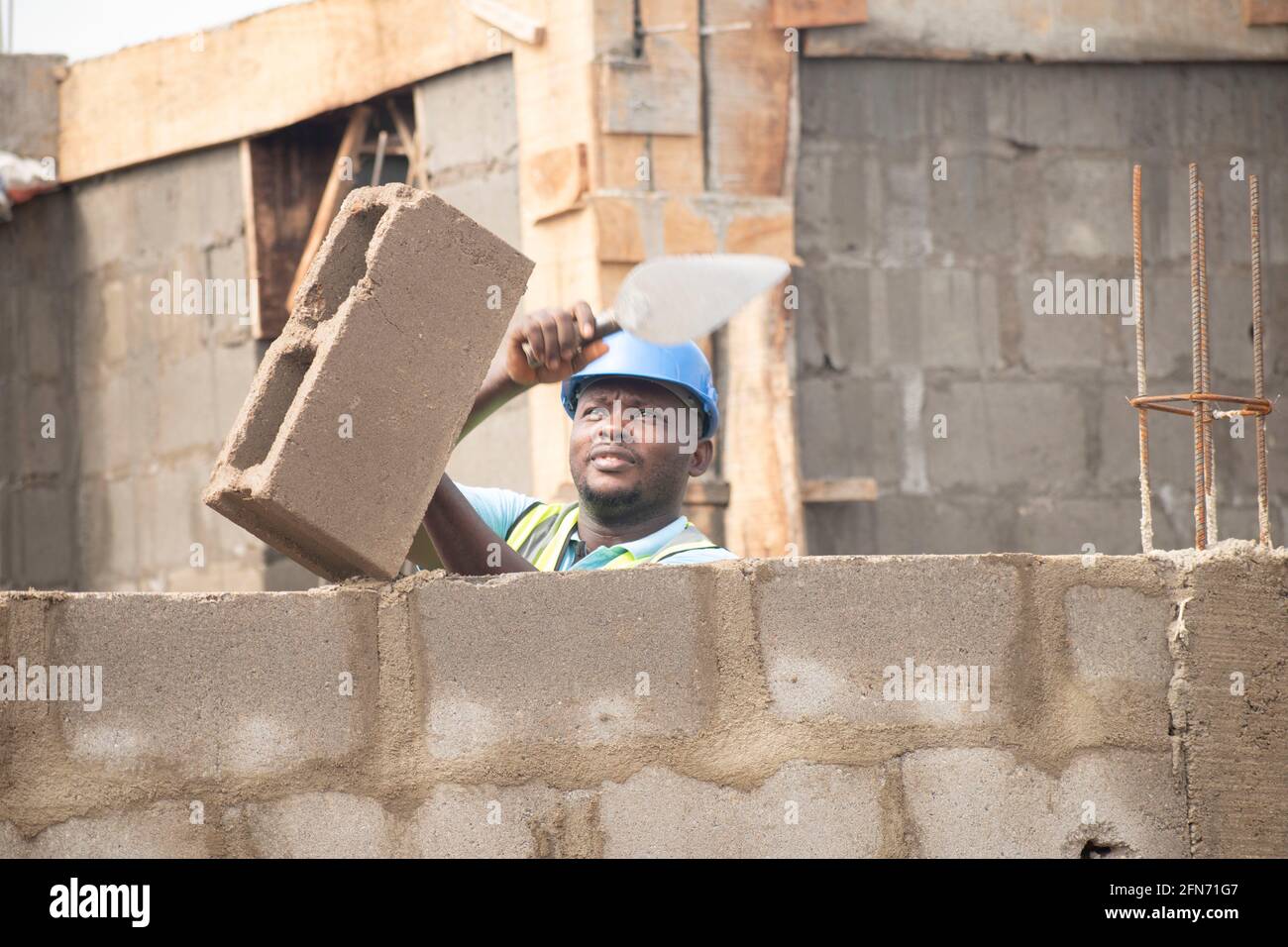 an african bricklayer laying bricks and holding a trowel Stock Photo