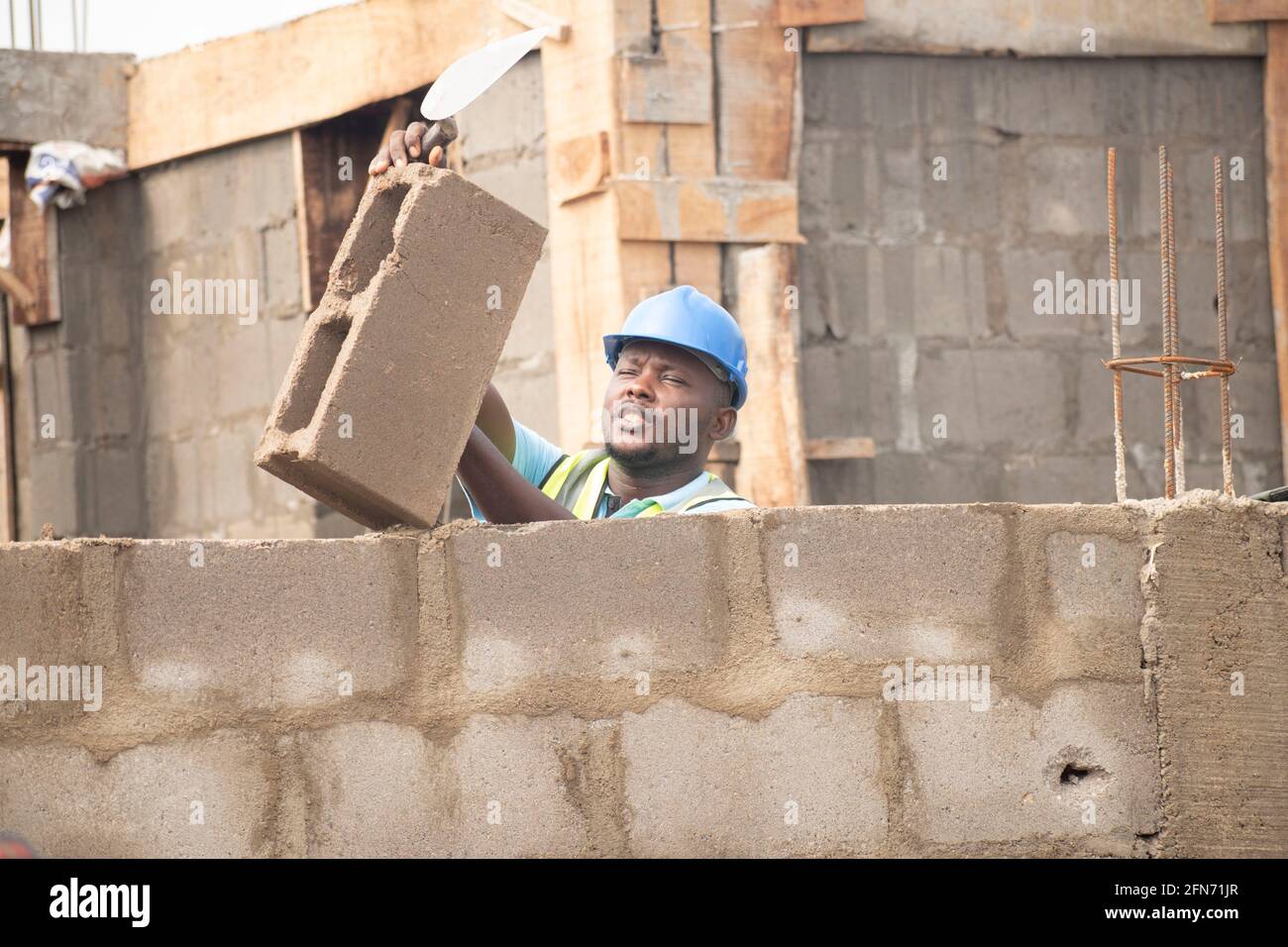 an african bricklayer laying bricks and holding a trowel Stock Photo