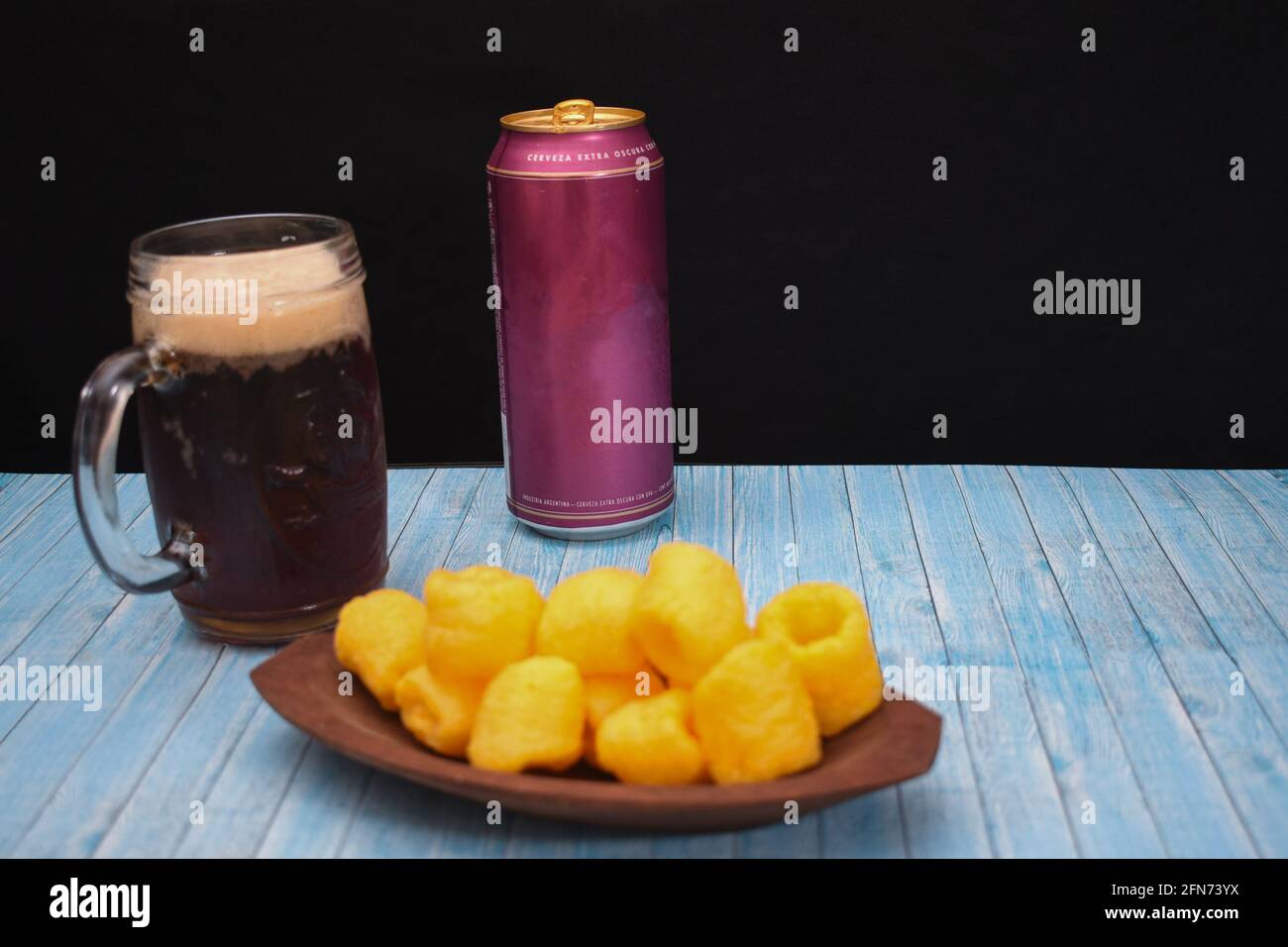 Colorful can of beer on a table with a filled mug and chips Stock Photo