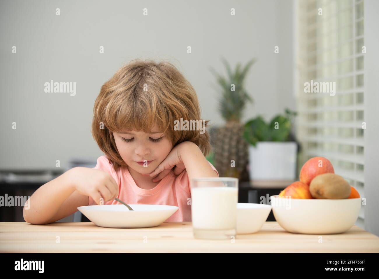 Food and drink for kids. Caucasian toddler child boy eating healthy soup in the kitchen. Stock Photo