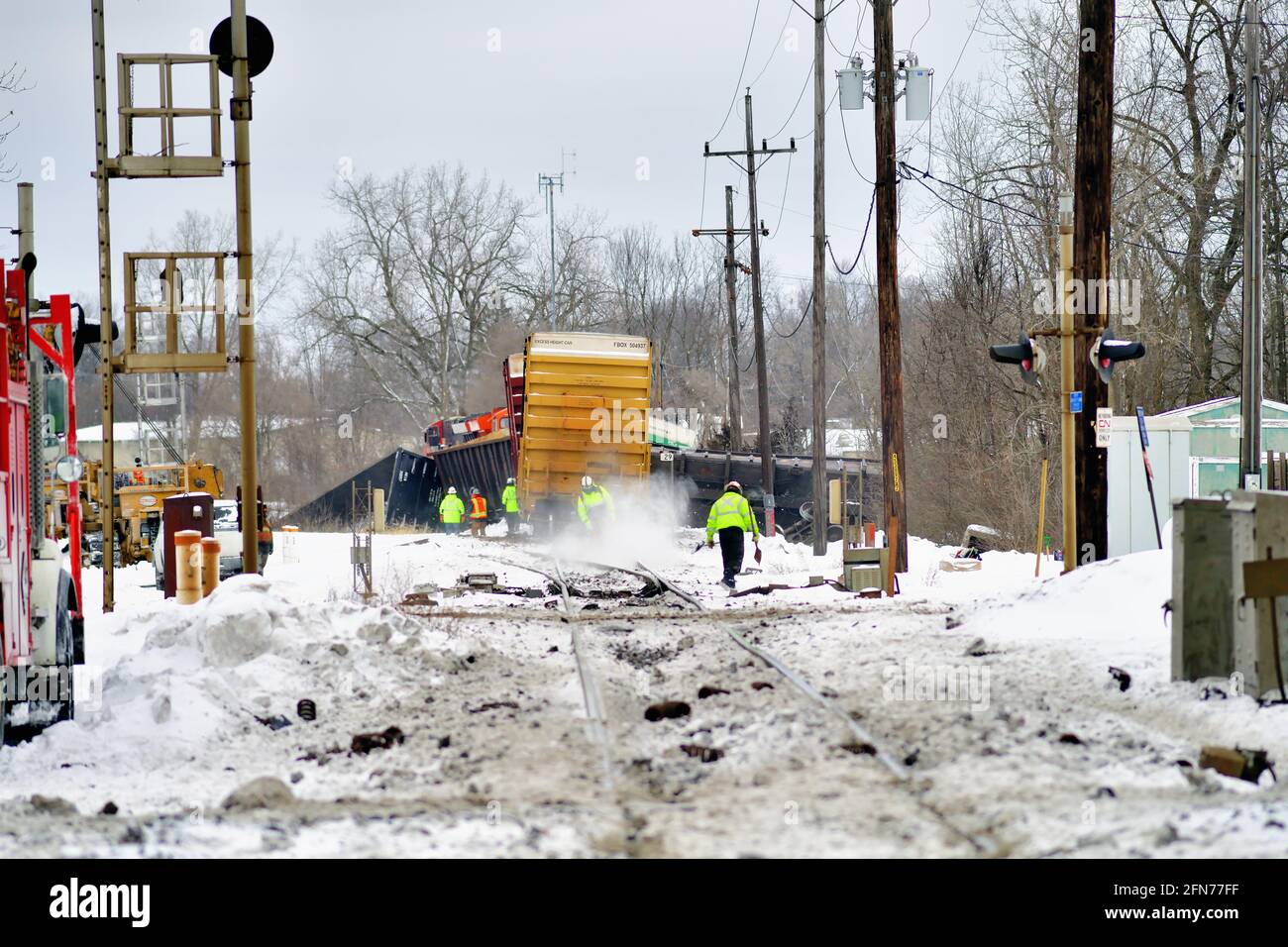 West Chicago, Illinois, USA. Workmen react to a Canadian National Railway freight train derailment that left freight cars scattered about the snow. Stock Photo