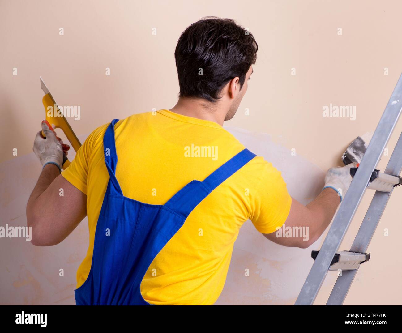The young contractor employee applying plaster on wall Stock Photo