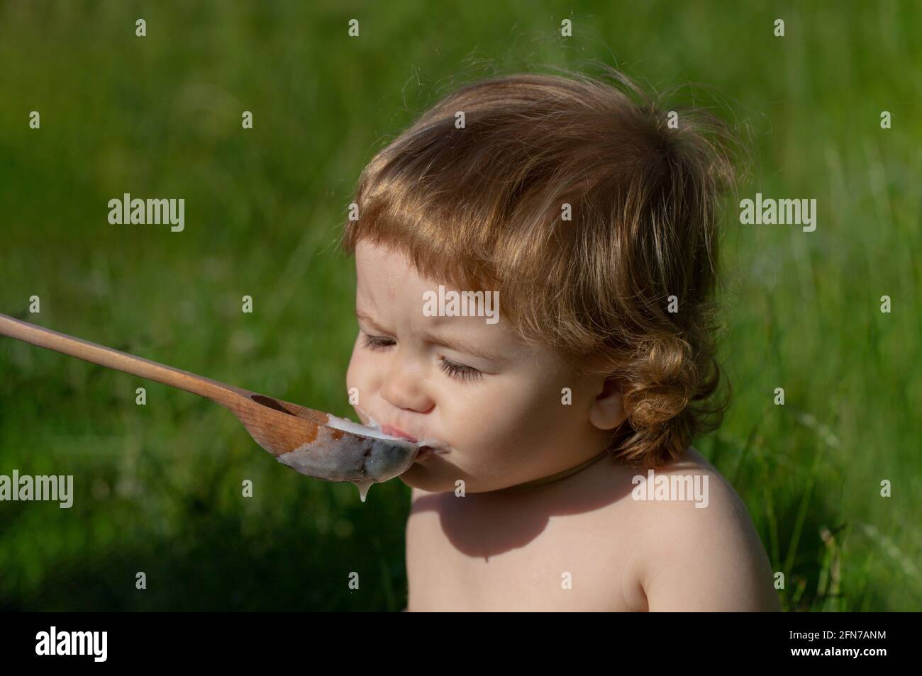 Cute toddler baby eating healthy food. Feeding with spoon. Funny child face. Stock Photo
