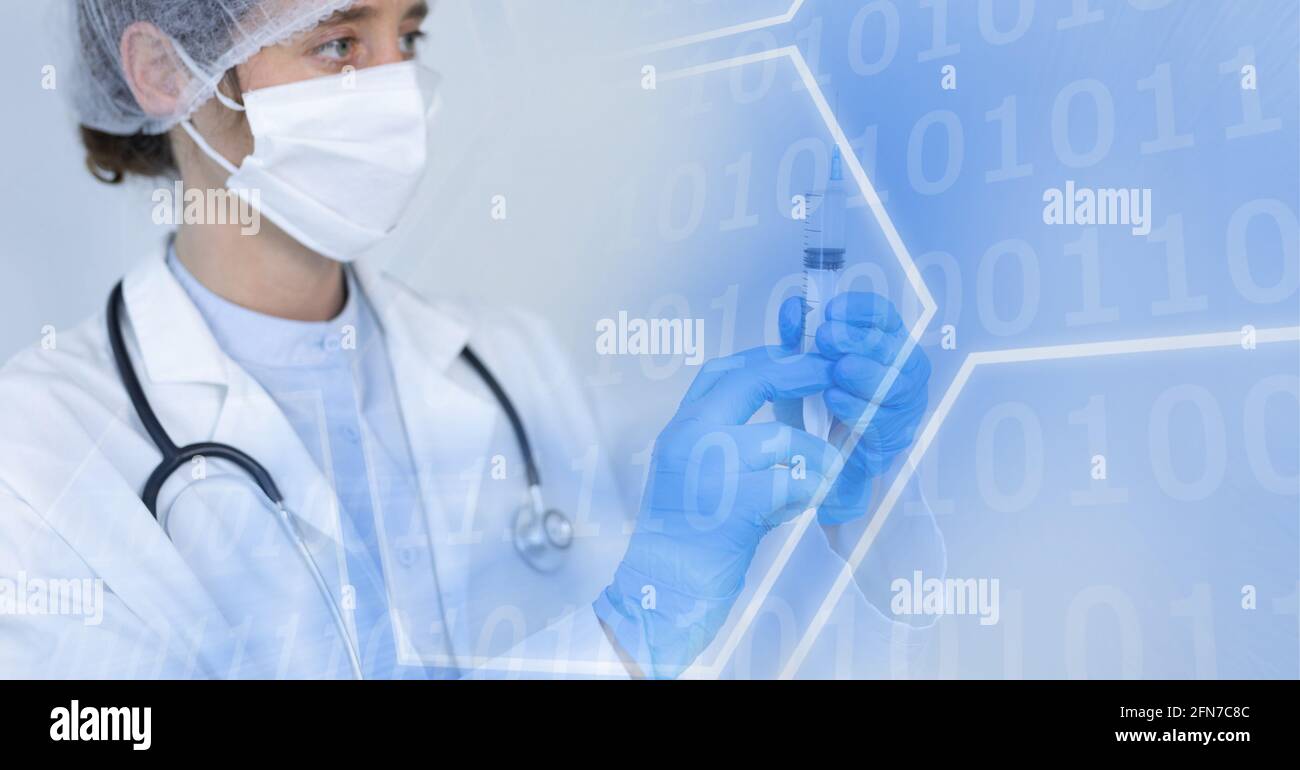 Composition of binary coding over doctor in face mask with syringe Stock Photo