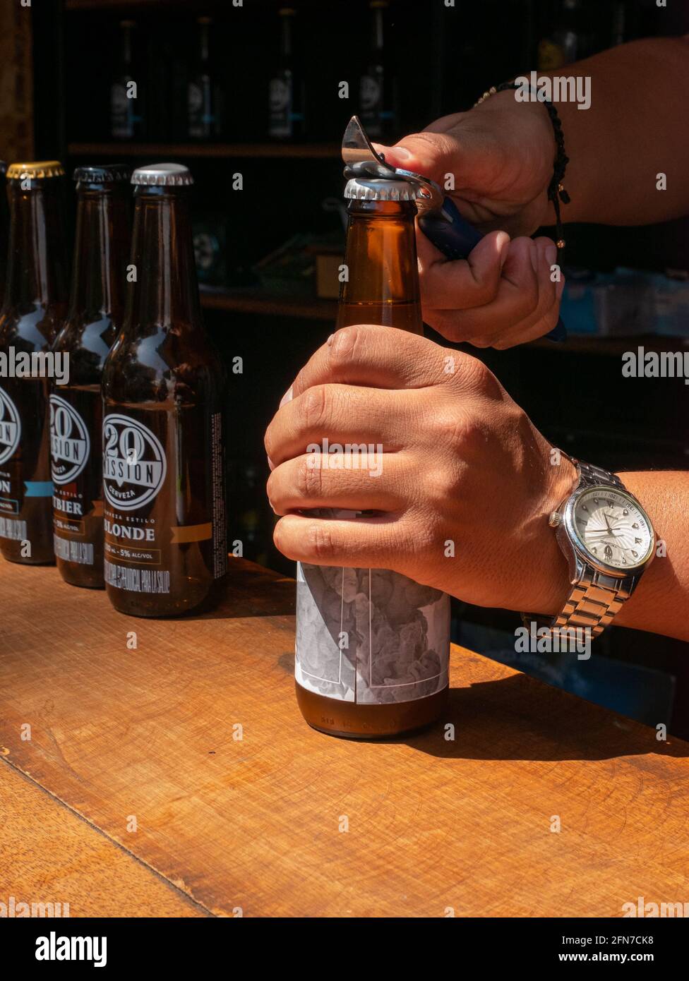 Medellin, Antioquia, Colombia - December 23 2020: Man's Hands opening a Handcraft Beer in a Bar Stock Photo