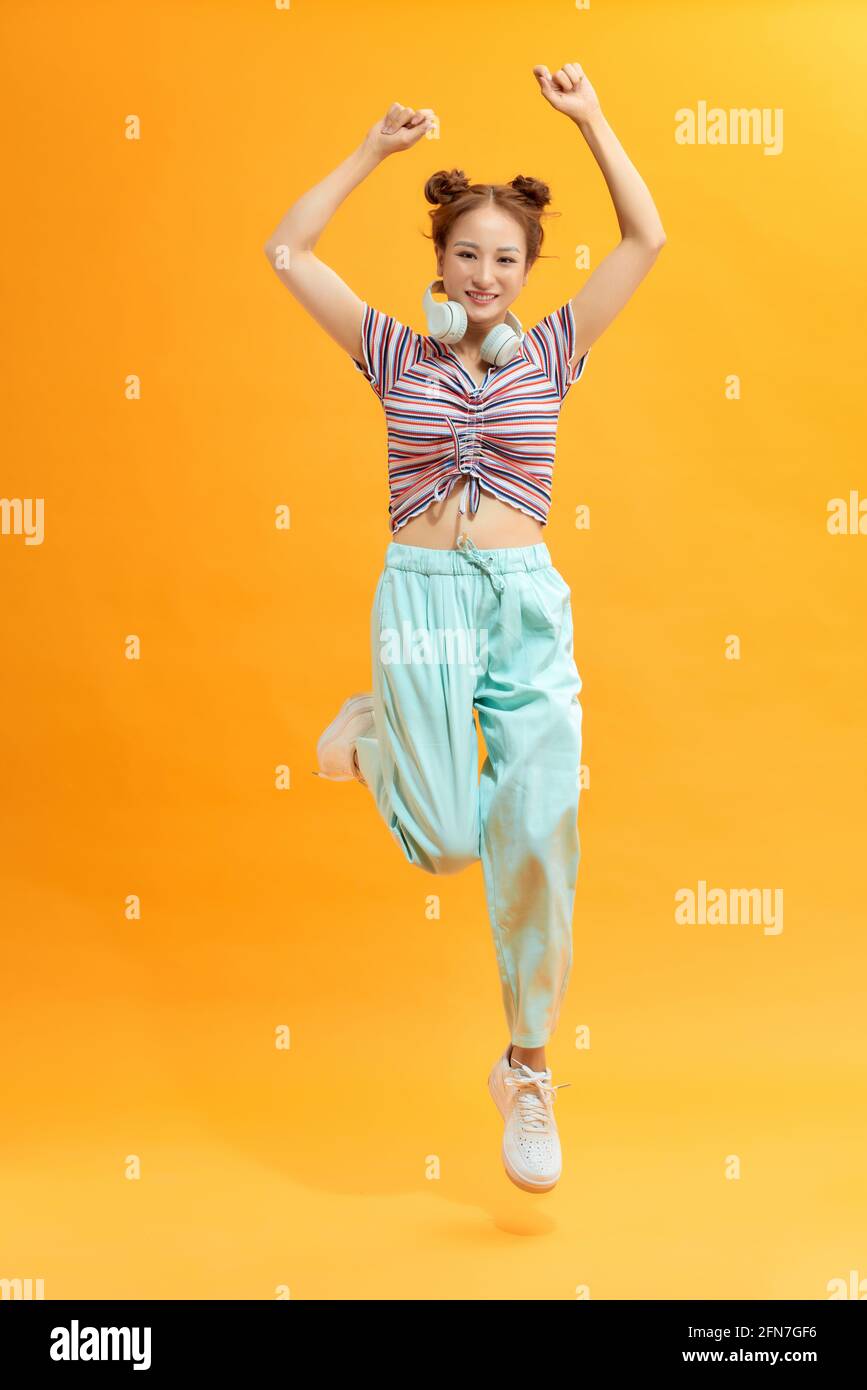 Lady in great mood jumping with raised hands on yellow background Stock ...