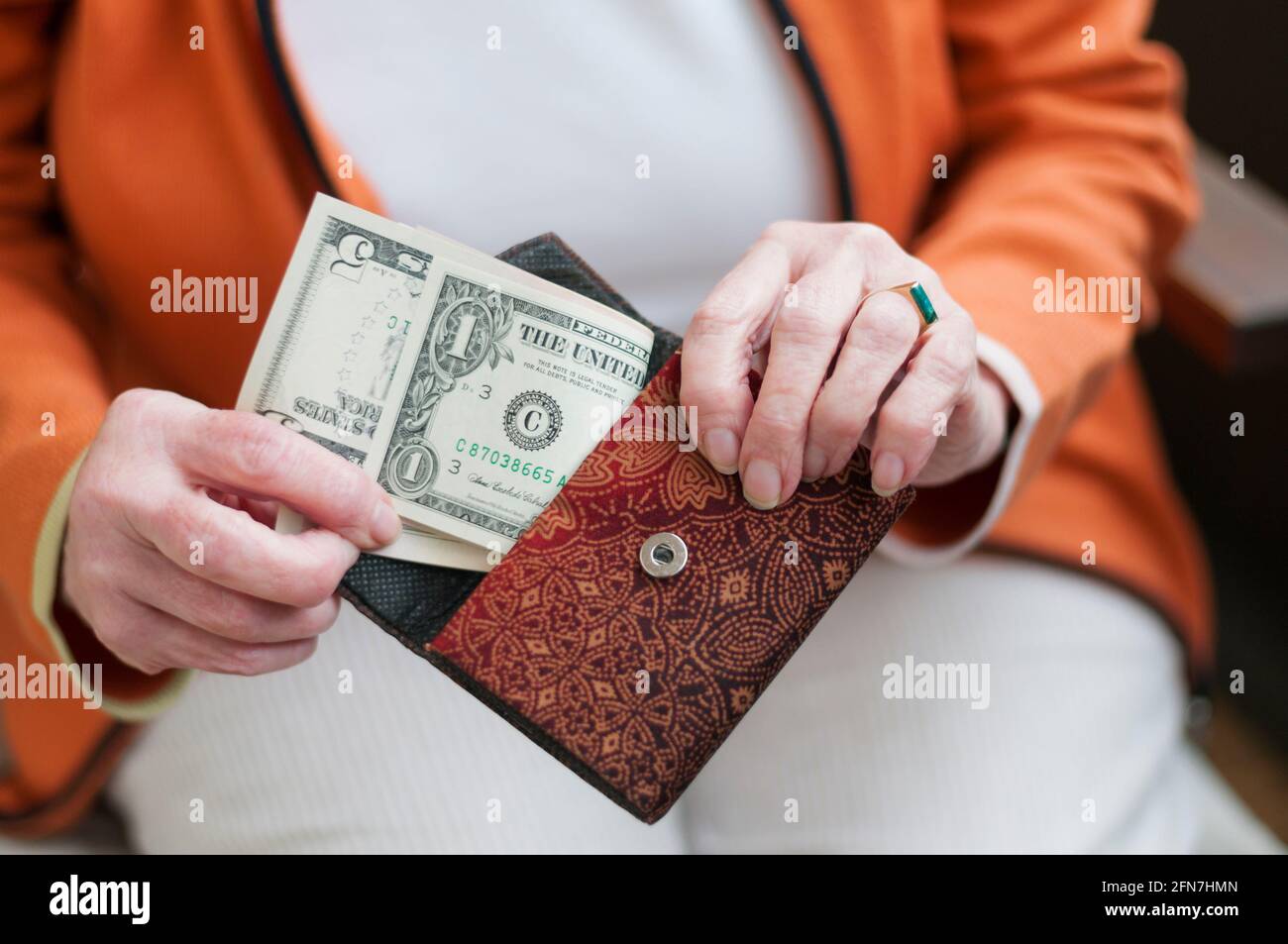 Senior women looks in her purse with US dollar bills. Stock Photo