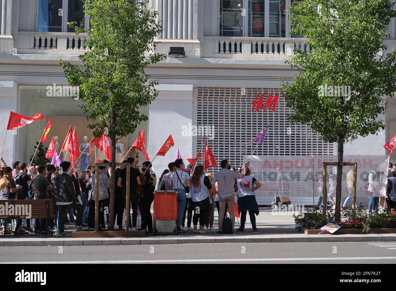 Madrid, Spain. May 14, 2021: Group of people protesting with CCOO, UGT and Juventud comunista flag in front of a H&M shop because of an ERE for 1100 w Stock Photo