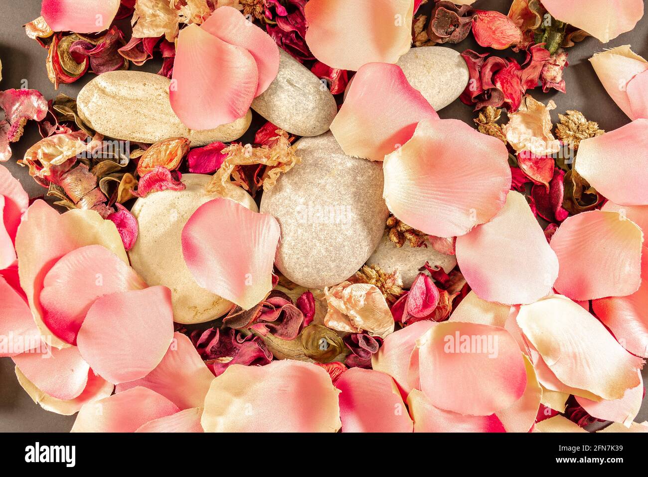 Wallpaper of dried flowers, flower petals and beach stones.Photo shot in horizontal format and zenithal point of view. Stock Photo