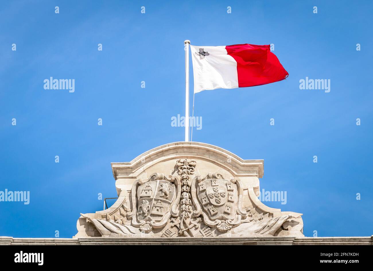 Maltese white and red flag against a blue sky - Top of prime minister building parliament in La Valletta capital of Malta mediterranean island Stock Photo