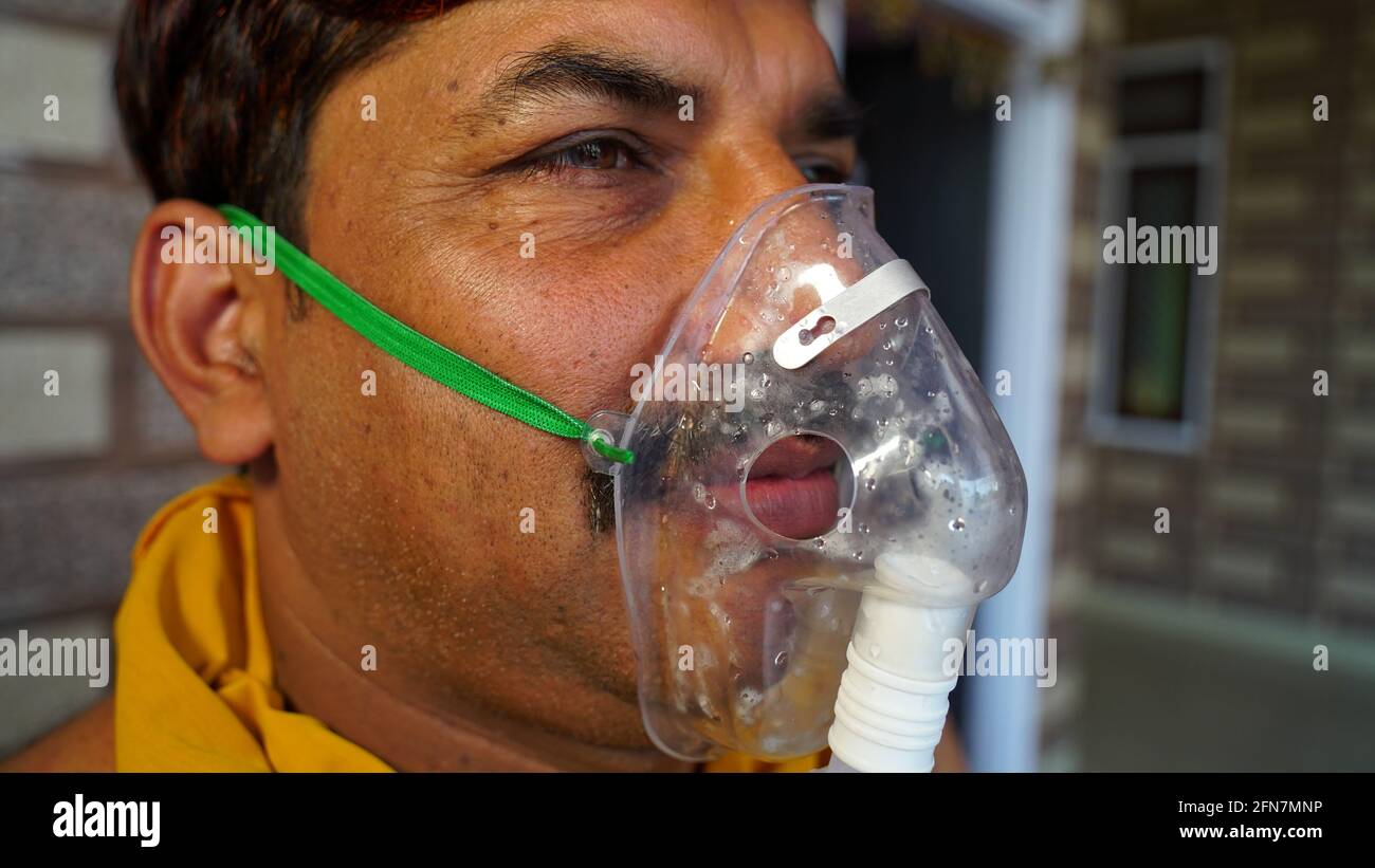 Man suffering from Covid 19 disease. Man admitted in hospital and inhaling emergency oxygen with canula mask. Stock Photo