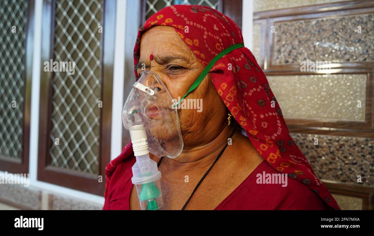 03 May 2021- Reengus, Sikar, India. Woman suffering from Covid 19 disease. Old woman admitted in hospital and inhaling emergency oxygen with canula ma Stock Photo