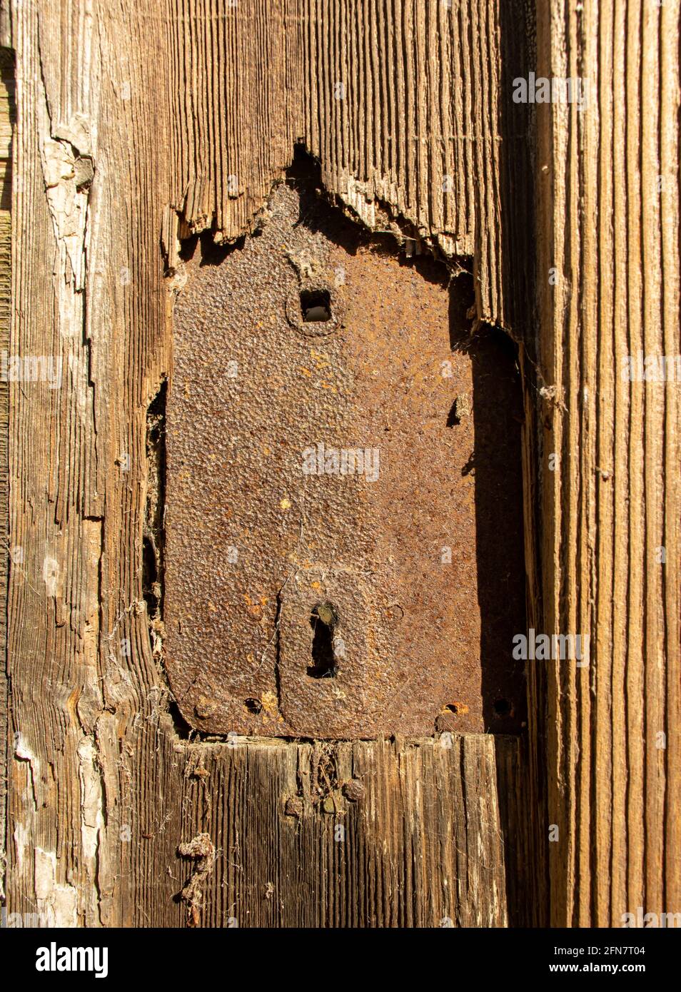 A rusty lock in an ancient door illuminated by the sun Stock Photo