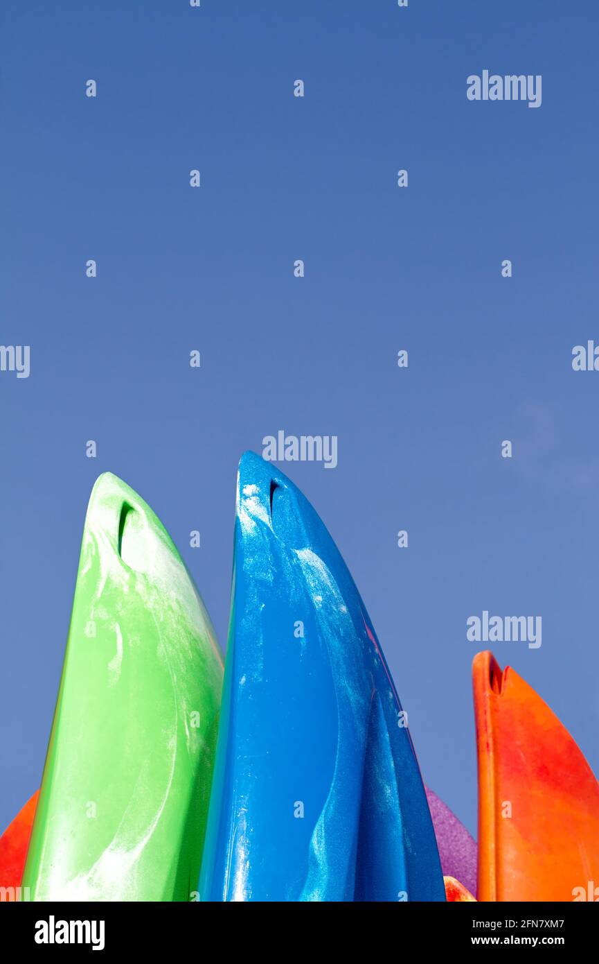 Bows Of Plastic Colourful Kayaks, Canoes Standing Upright Against A Blue Sky, UK Stock Photo