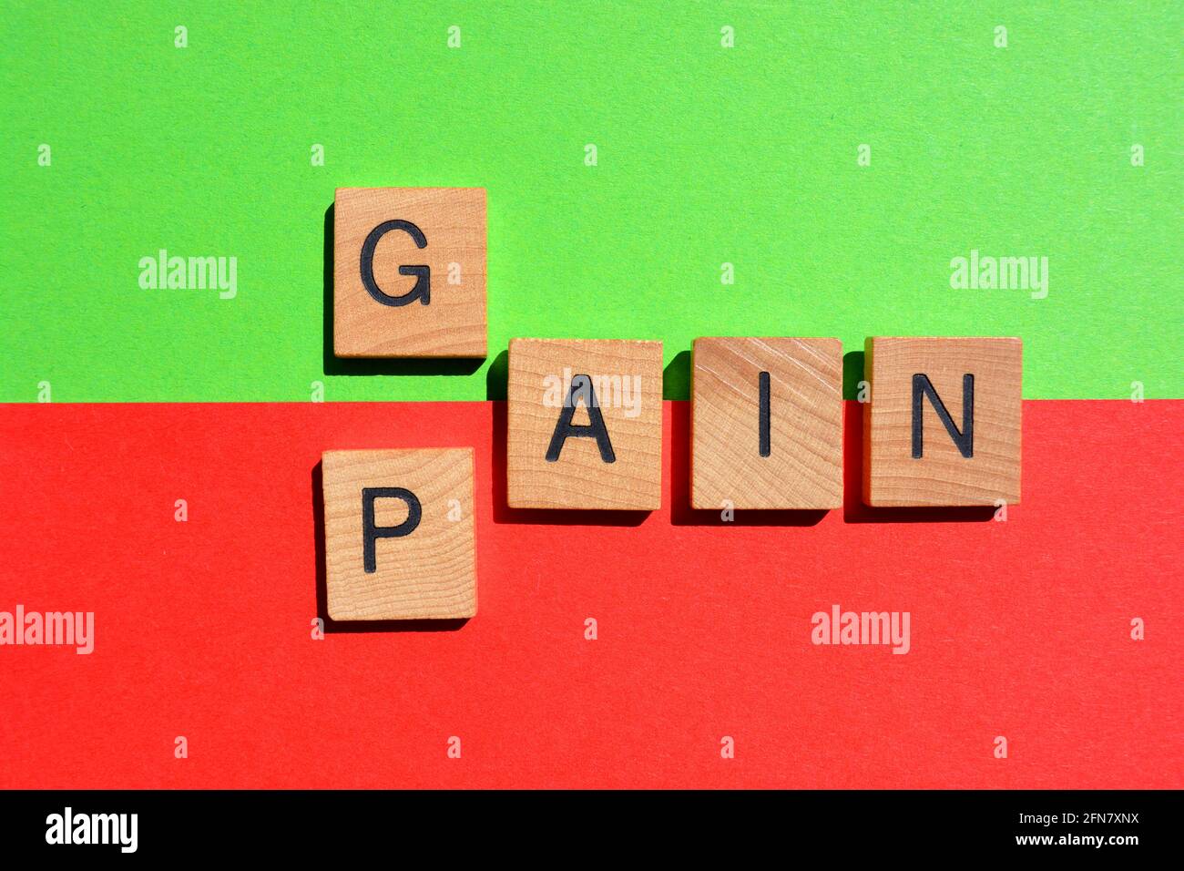 Gain, Pain, words in wooden alphabet letters isolated on green and red background Stock Photo