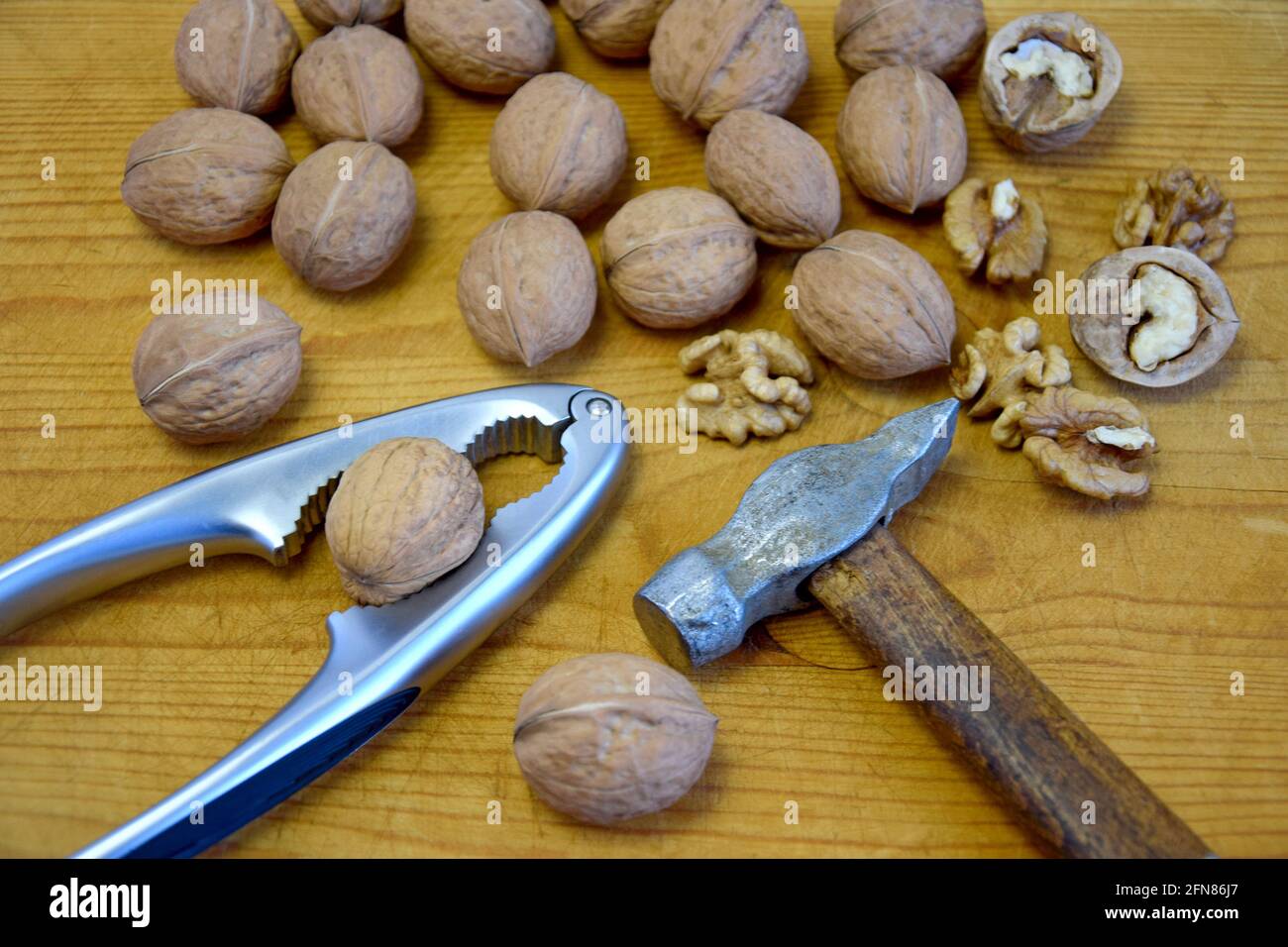 Walnuts, nutcracker and old hammer on wooden background. Close-up. Selective focus. Stock Photo