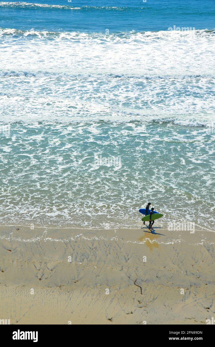 Seascape with panoramic view of two surfers walking with their
