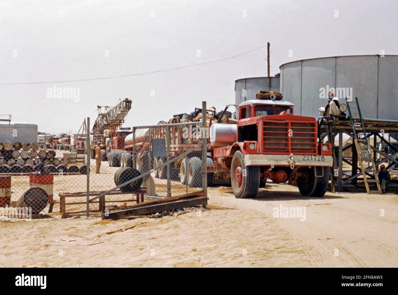 Oil exploration by the petroleum company Aramco in Saudi Arabia c. 1955. Here a convoy of trucks leaves a depot to head out to exploration sites. The vehicles carry camping equipment, mobile homes/offices and test-drilling rigs. Water tankers form part of the convoy. Saudi Aramco (now the Saudi Arabian Oil Company and formerly Arabian-American Oil Company) is a Saudi Arabian petroleum and natural gas company based in Dhahran. . In 1944 the company name was changed from California-Arabian Standard Oil Company to Arabian-American Oil Company (or Aramco) – a vintage 1950s photograph. Stock Photo
