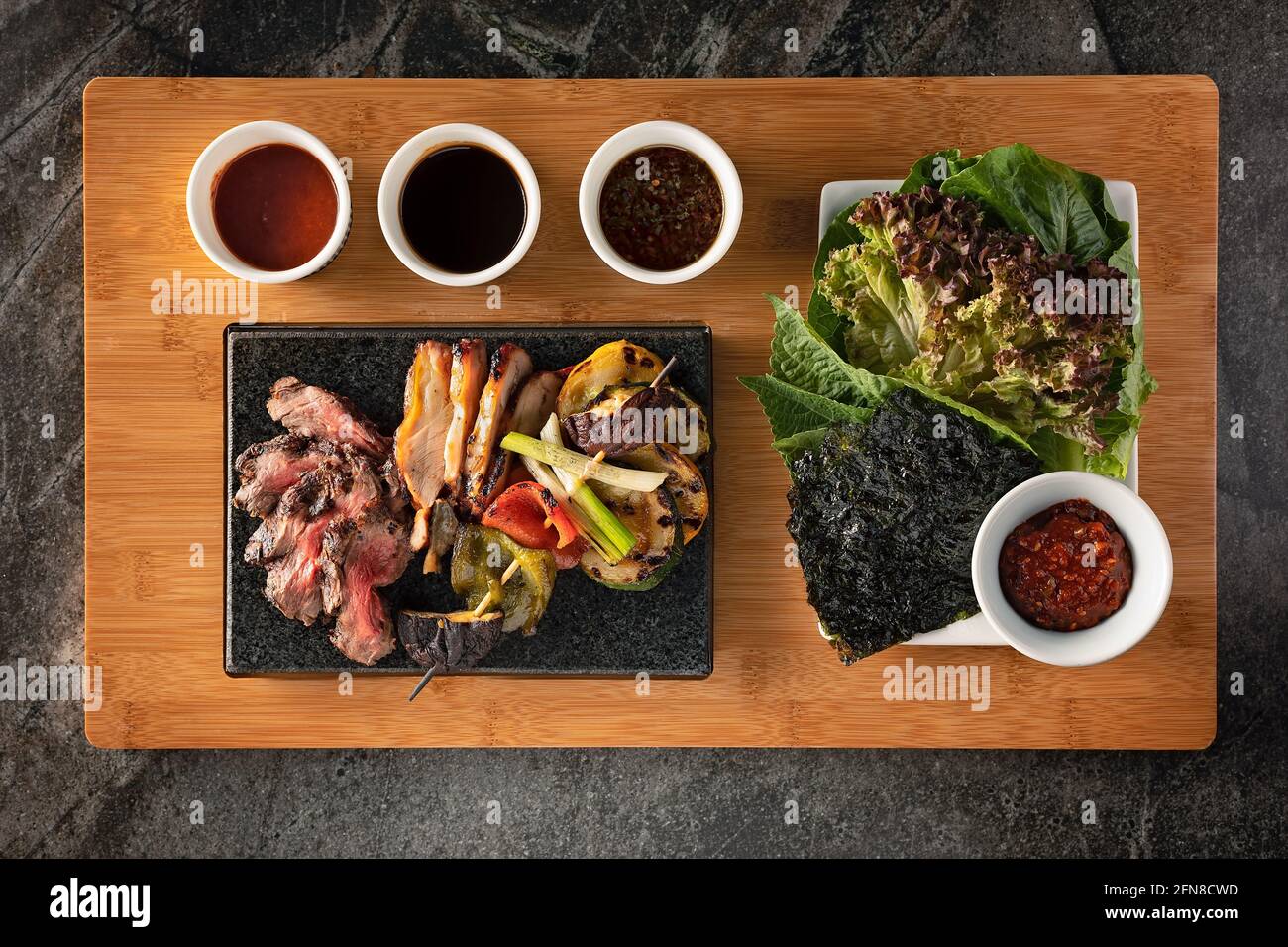 Flat lay of beef and pork platter with grilled vegetables, seaweed and