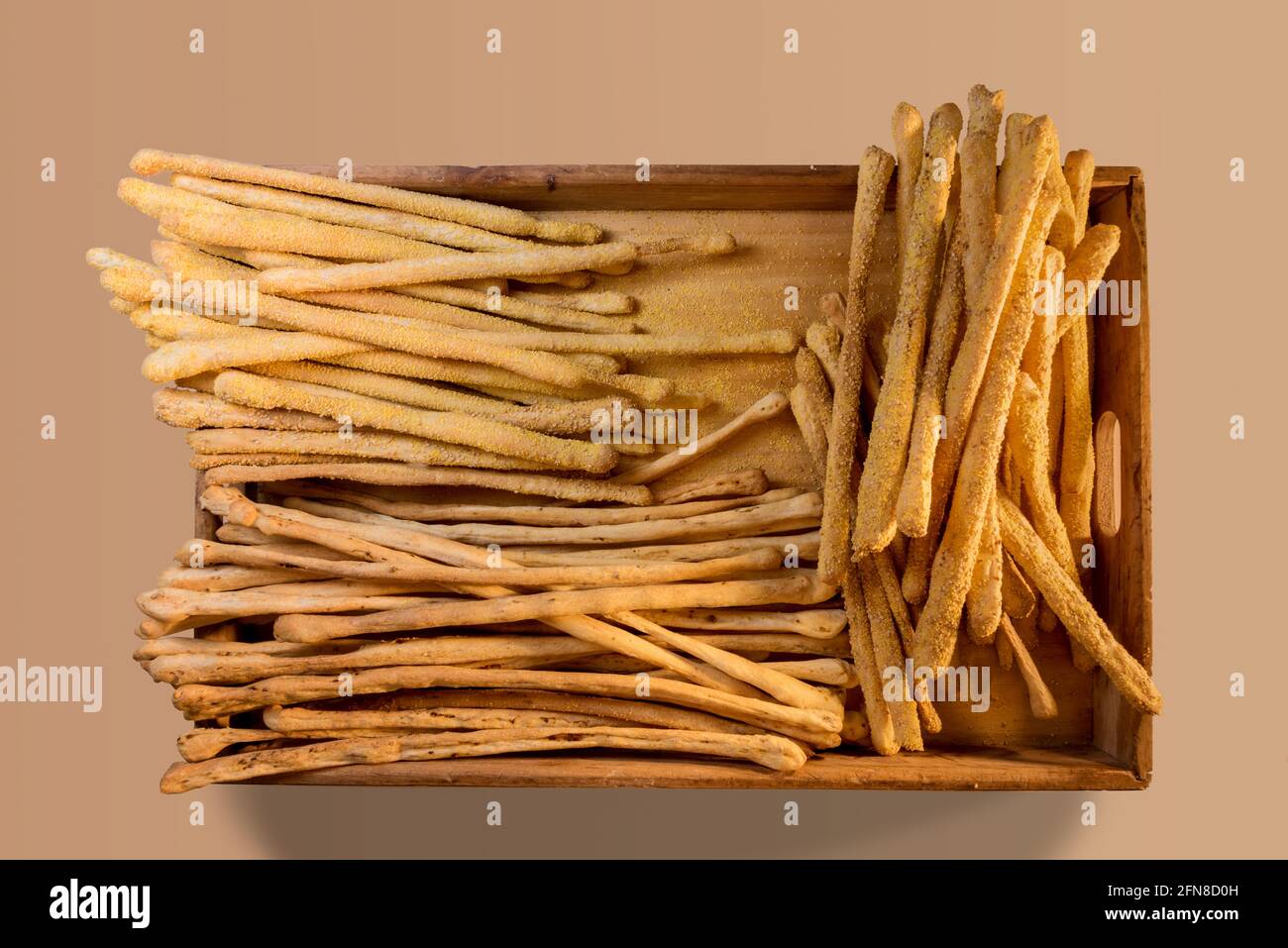 Italian breadsticks with sesame seeds and with olives in wooden tray on beige background in top view Stock Photo