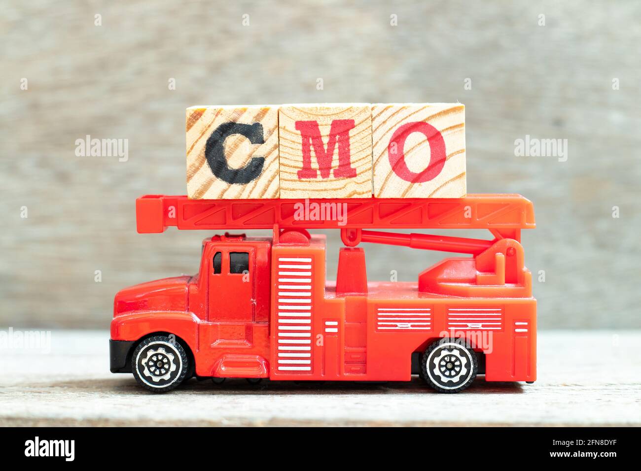 Fire ladder truck hold letter block in word CMO (Abbreviation of Chief Marketing Officer, Contract Manufacturing Organization) on wood background Stock Photo