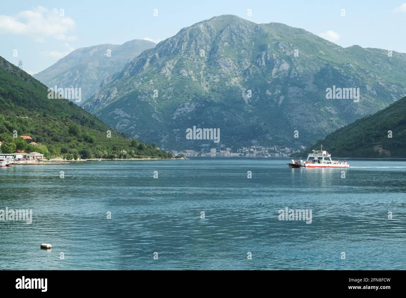 Picture of the bay of Kotor during a sunny afternoon,with a ferry boat in front of the mountains of Balkans. The Bay of Kotor is the name of the windi Stock Photo