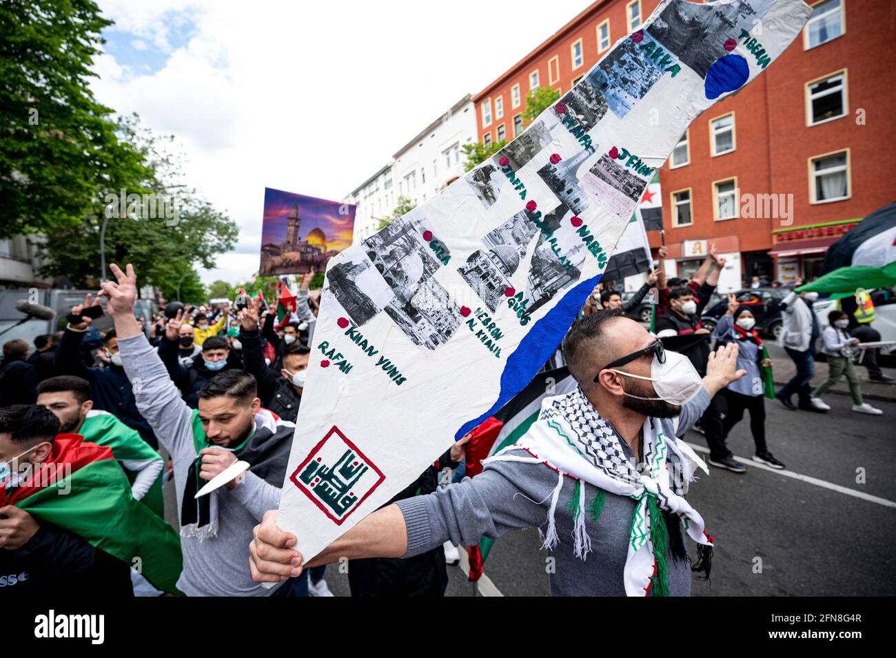 Berlin, Germany. 15th May, 2021. A participant of the demonstration of various Palestinian groups walks through Neukölln with a map of Israel and the Palestinian Autonomous Territories. On the annual Nakba commemoration day on May 15, Palestinians remember the flight and expulsion of hundreds of thousands of Palestinians from the territory that later became Israel. Credit: Fabian Sommer/dpa/Alamy Live News Stock Photo