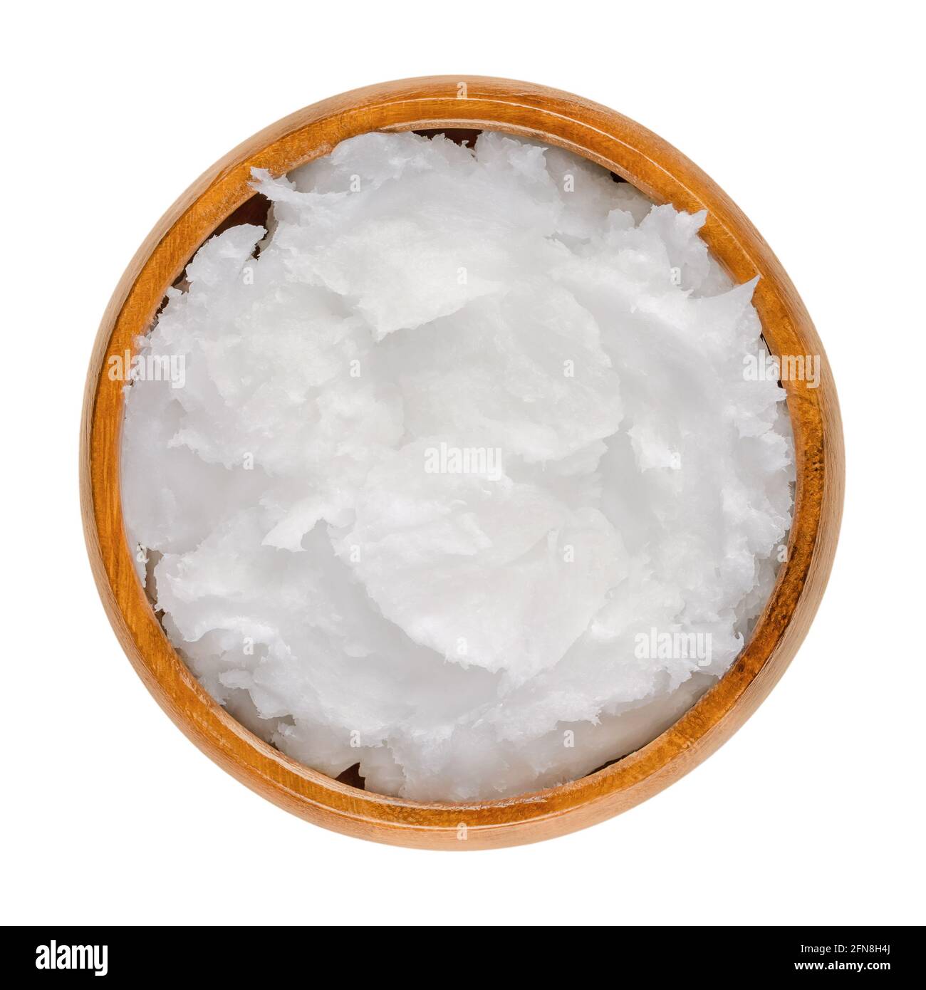 Coconut oil in a wooden bowl. Unrefined coconut butter, an edible oil, derived from the wick, meat, and milk of the coconut palm fruit. Stock Photo
