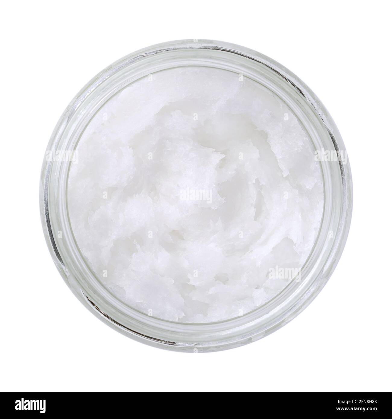 Coconut oil in a glass jar. Unrefined coconut butter, an edible oil, derived from the wick, meat, and milk of the coconut palm fruit. White solid fat. Stock Photo