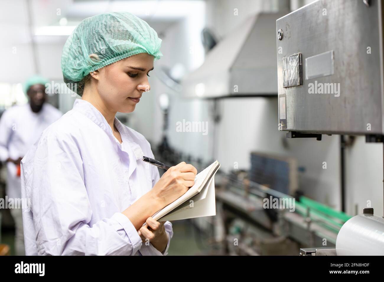 Quality control and food safety caucasian women worker staff inspection the product standard in the food and drink factory production line. Stock Photo
