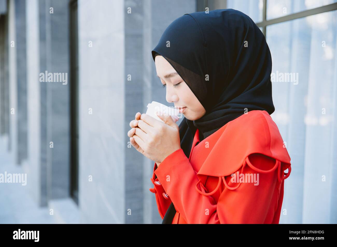 Arab Muslim women drinking coffee in the morning outdoor, Asian businesswoman young girl smiling hand hold coffee cup standing closeup. Stock Photo
