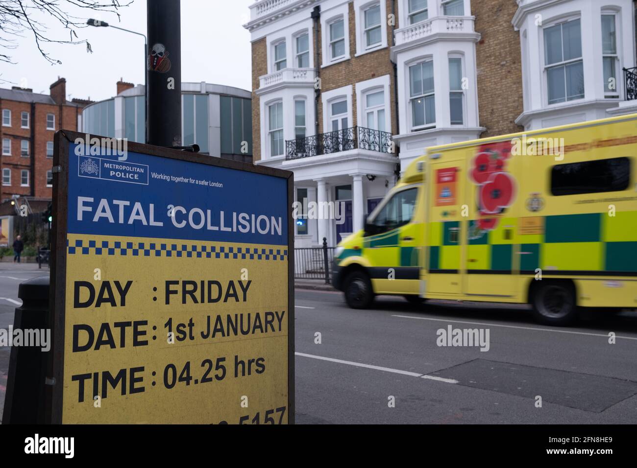 West London, March 2021:  A police notice of fatal car crash and call for witness information, with an ambulance driving past in background Stock Photo