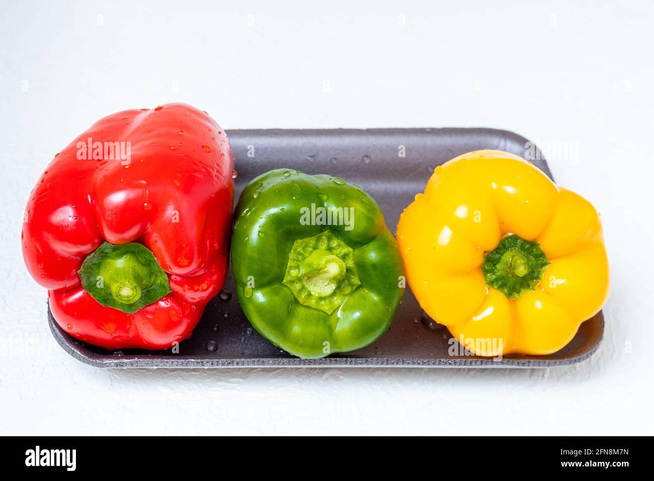 Three bright Bulgarian sweet peppers red yellow and green in a