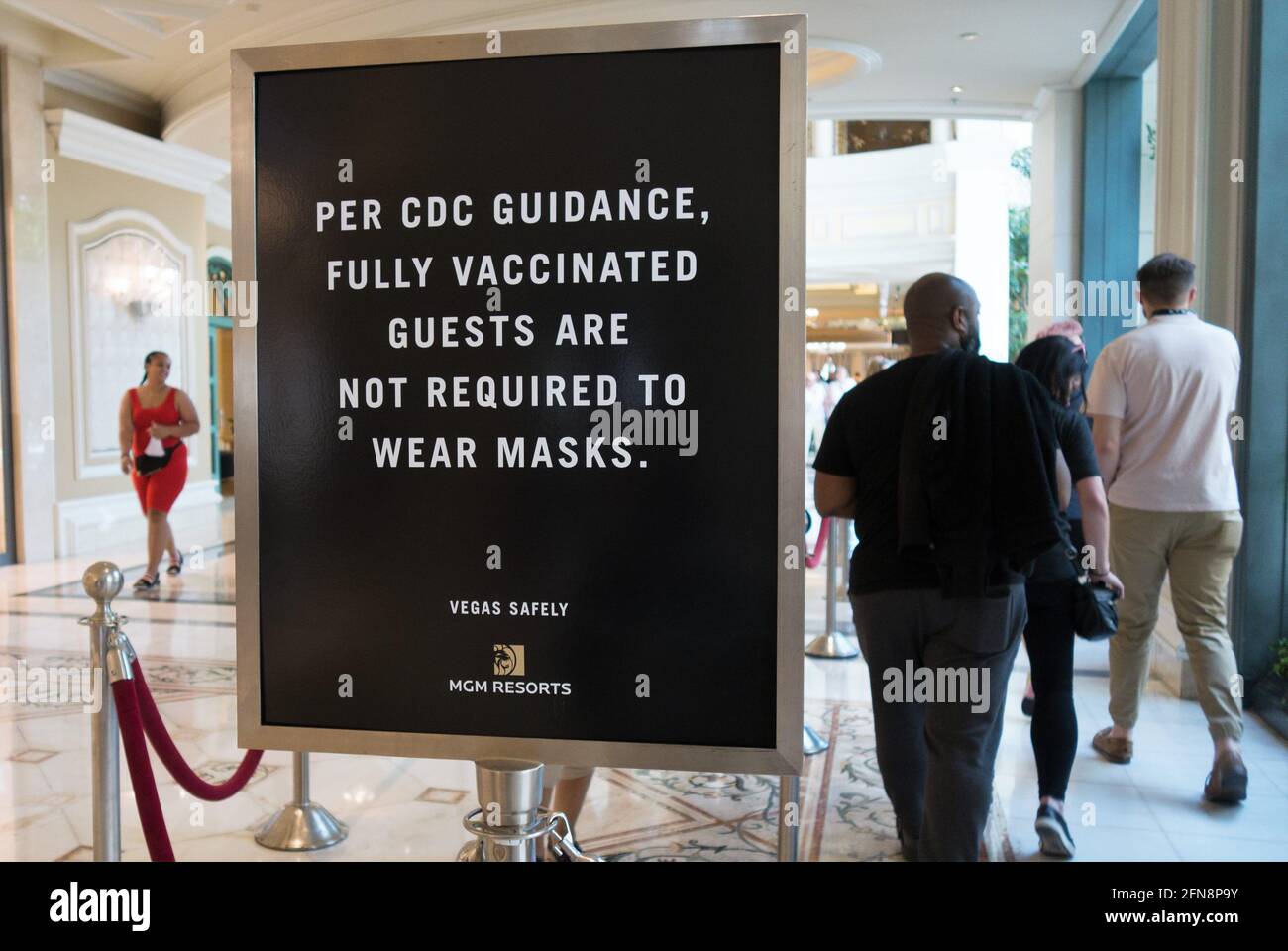 Unmasked people walking near a sign that states fully vaccinated guests are not required to wear masks, at the Bellagio Hotel in Las Vegas, Nevada. Stock Photo