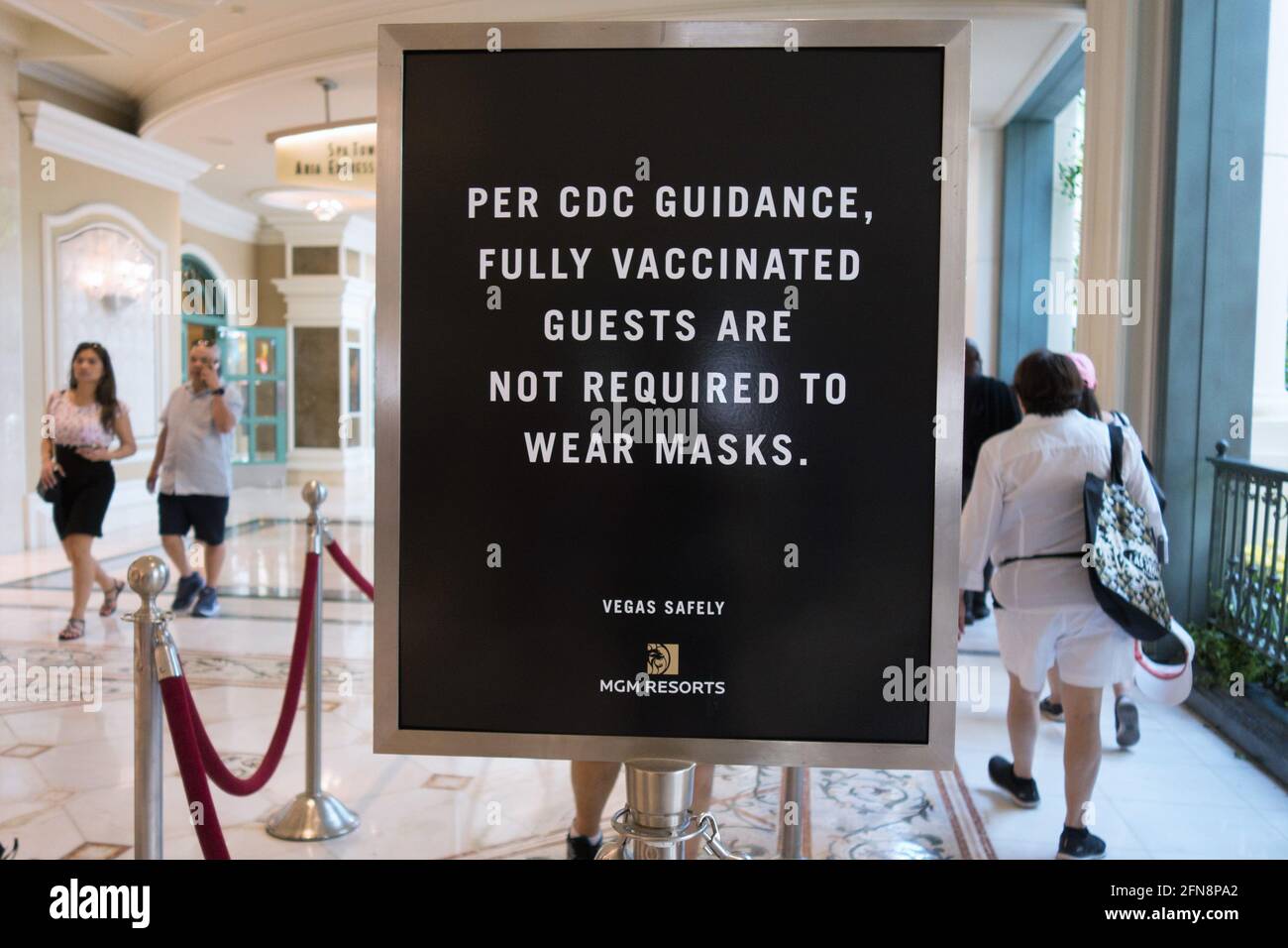Unmasked people walking near a sign that states fully vaccinated guests are not required to wear masks, at the Bellagio Hotel in Las Vegas, Nevada. Stock Photo