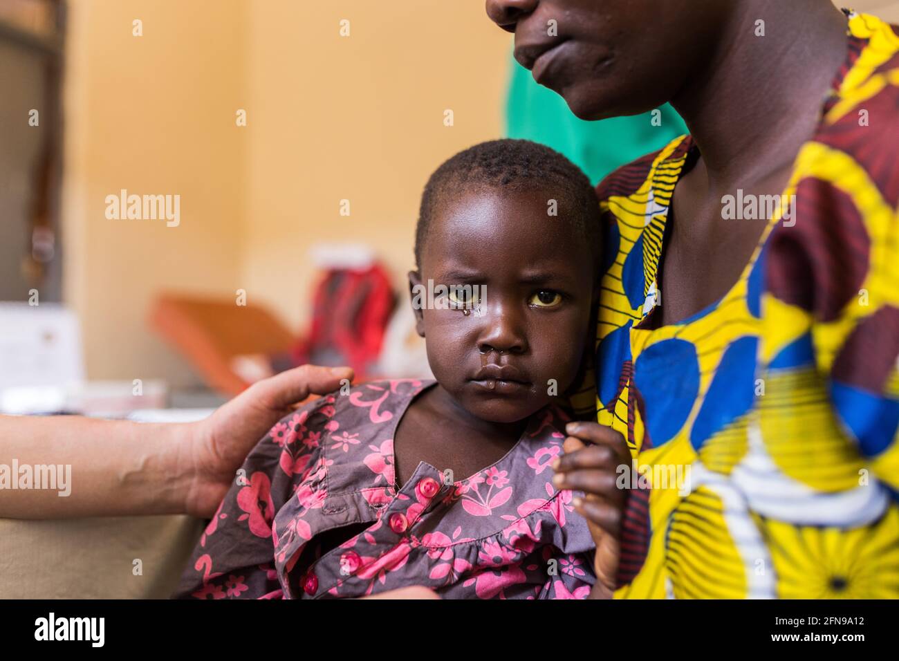 Sick young girl with her mother in a medical clinic in Mbale, rural Eastern Uganda Stock Photo