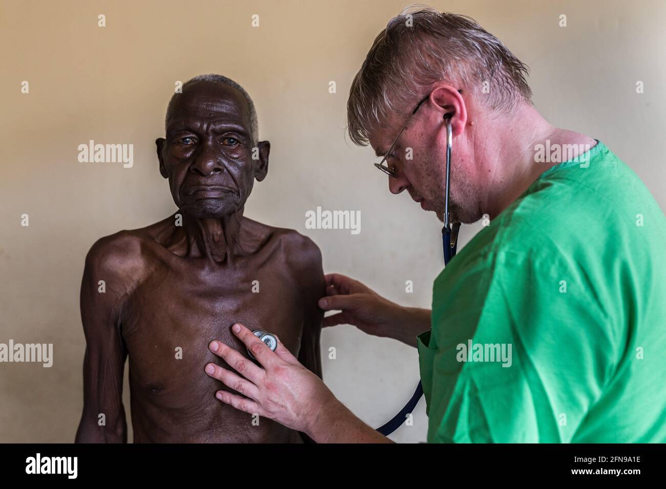 Foreign doctor is examining an elderly man in a medical clinic in Mbale, rural Eastern Uganda Stock Photo