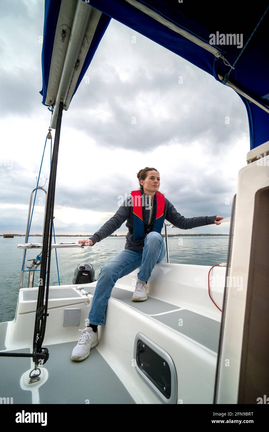 Woman wearing a life jacket sailing a yacht. Stock Photo
