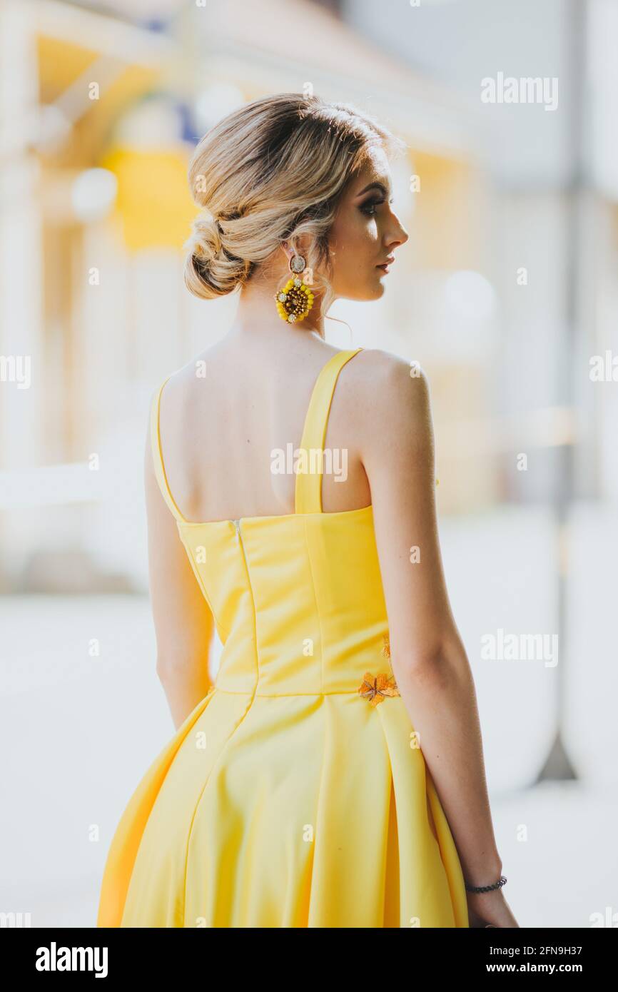 Vertical portrait of a gorgeous Caucasian blonde female in an elegant  yellow dress looking aside Stock Photo - Alamy