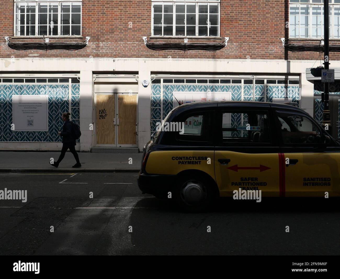 London, Greater London, England - May 11 2021: Shop boarded up on Thayer Street in Marylebone during lockdown as a taxi and pedestrian pass by. Stock Photo