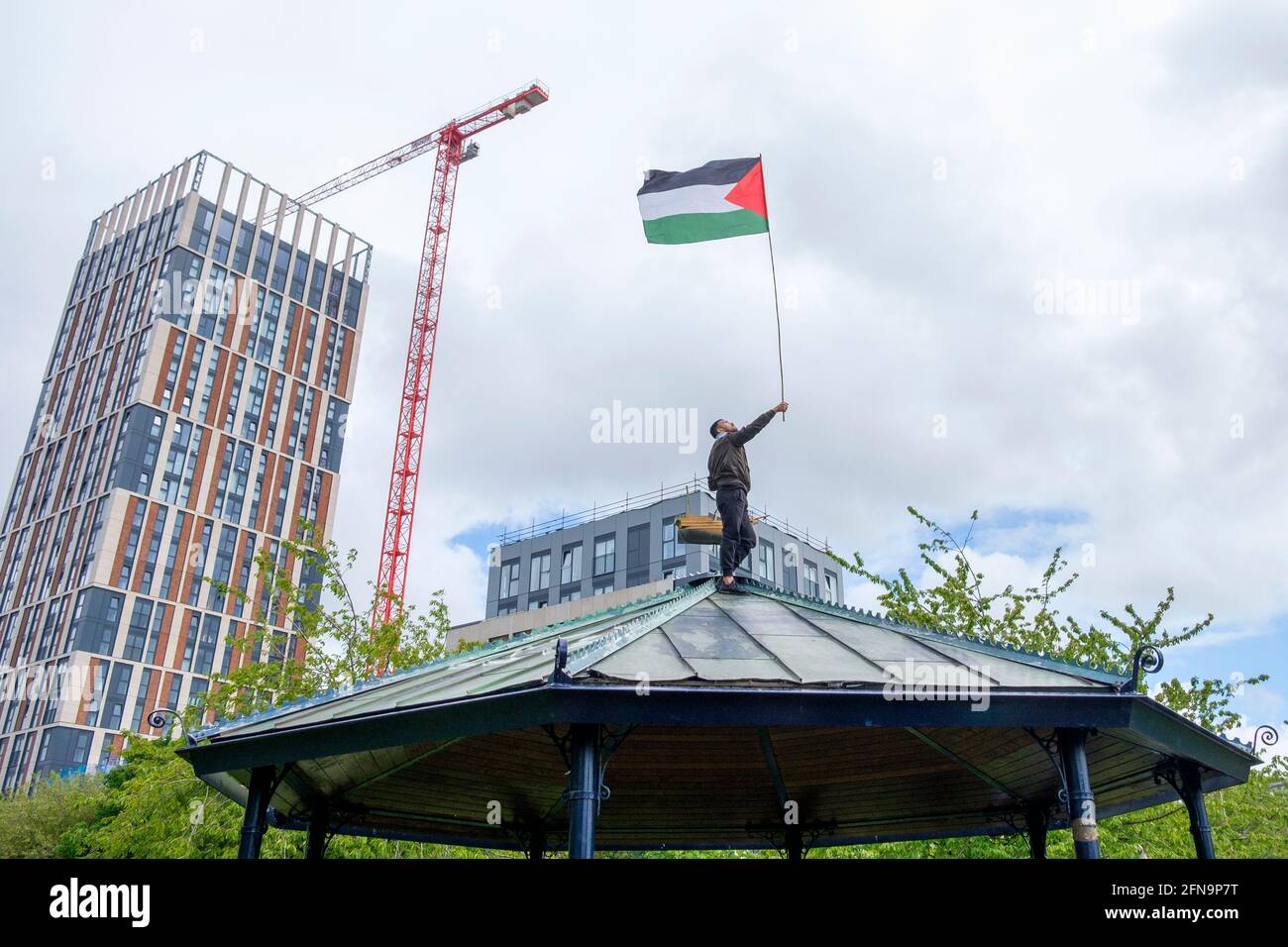 Bristol, UK. 15th May, 2021. A Pro-Palestinian protester is pictured waving a Palestinian flag on top of a band stand in Castle Park as Pro-Palestinian supporters listen to speeches after a Pro-Palestinian protest march through Bristol. The protest march and rally was held to allow people to show their support and solidarity with the Palestinian people after 73 Years of Nakba and to protest about Israel's recent actions in Gaza. Credit: Lynchpics/Alamy Live News Stock Photo