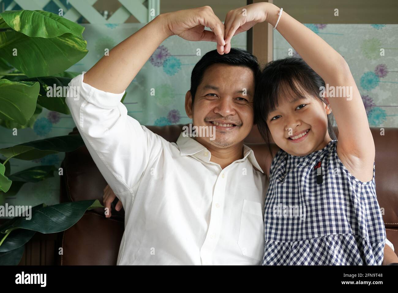 Father and playful cute small child daughter making heart symbol with fingers.Concept of happy fathers day Stock Photo