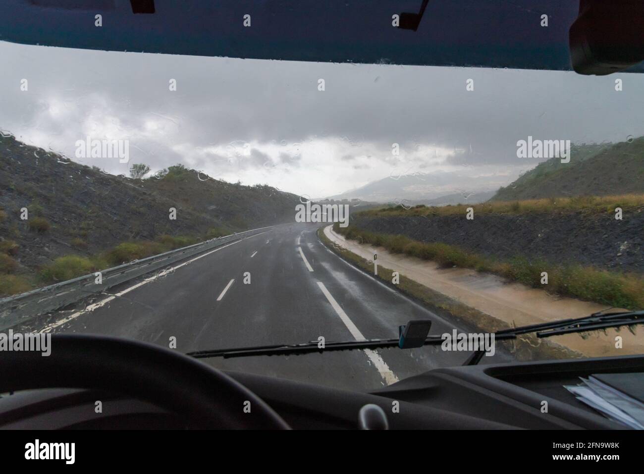 View of the highway from the driver's seat of a truck on a heavy rainy day. Stock Photo