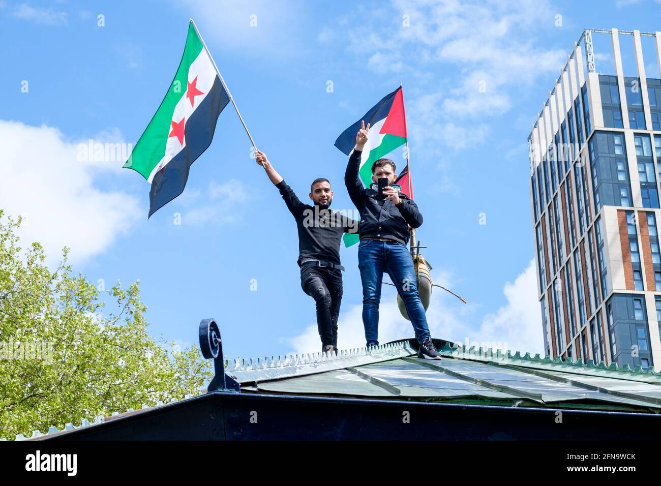 Bristol, UK. 15th May, 2021. Pro-Palestinian supporters are pictured waving a flag on top of a band stand in Castle Park as Pro-Palestinian supporters listen to speeches before a Pro-Palestinian protest march through Bristol. The protest march and rally was held to allow people to show their support and solidarity with the Palestinian people after 73 Years of Nakba and to protest about Israel's recent actions in Gaza. Credit: Lynchpics/Alamy Live News Stock Photo