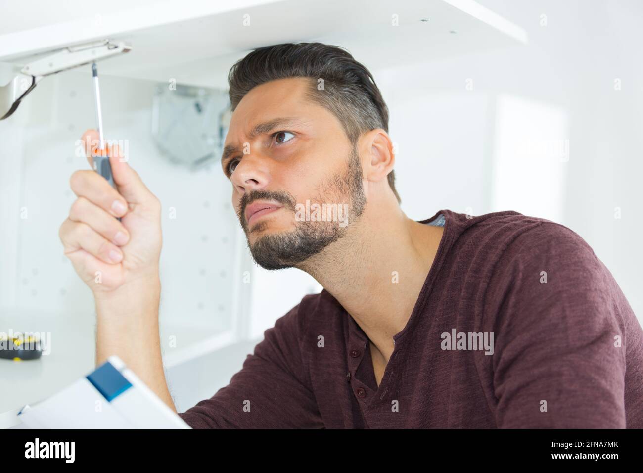 man with screwdriver installing shelf Stock Photo